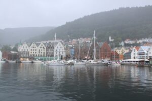 ノルウェー・ベルゲンのブリッゲン地区と港の風景。霧がかった山々とヨットが停泊する静かな水辺